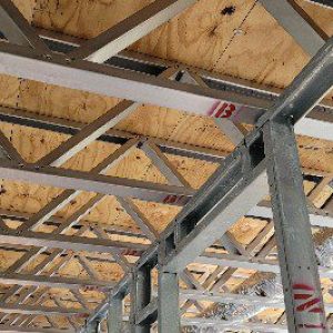 Exposed wooden ceiling with metal beams and support columns.