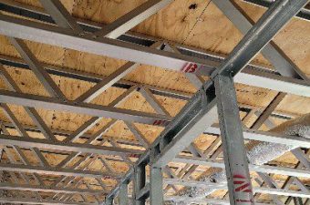 Exposed wooden ceiling with metal beams and support columns.