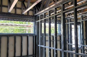 Interior view of a building under construction with metal framing and window openings.