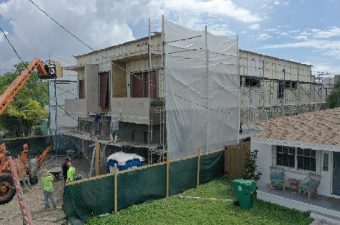 A house under construction covered with scaffolding and netting.