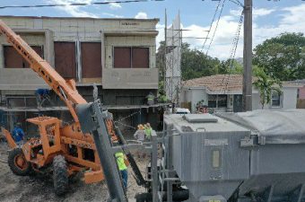 Construction machinery working near residential buildings on a street.
