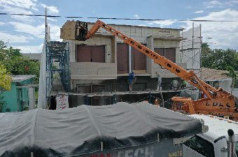 Crane lifting a large concrete panel onto a building under construction.