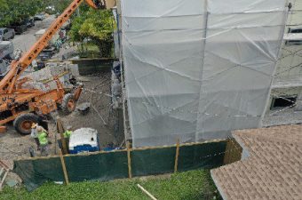 Construction site with covered building and machinery.