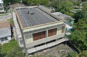 A building under construction with scaffolding and black roofing material.