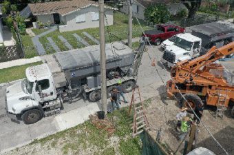 Workers operating heavy machinery on a construction site near residential houses.