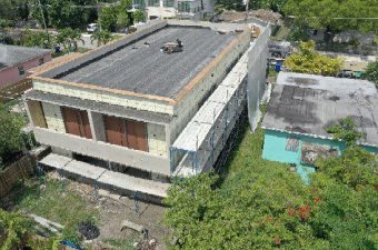 Aerial view of a rooftop with solar panels and surrounding greenery.