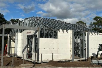 Steel frame structure of a house under construction on a sunny day.