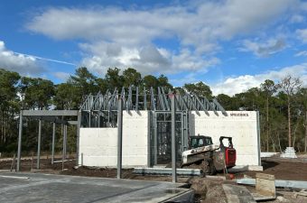Steel frame construction on a new building under a partly cloudy sky.