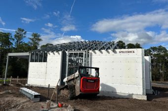 Construction site with insulated concrete forms being assembled under a blue sky.