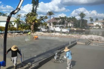Construction workers smoothing concrete on a sunny day.