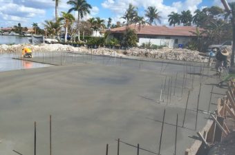 Concrete being poured at a construction site under a bright blue sky.