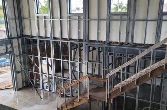 Interior construction with metal framing and wooden stairs.
