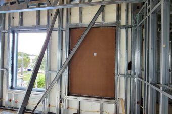 Framed wall with a brown panel in a metal stud structure.