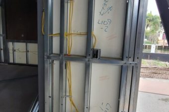 Exposed wiring and metal framing inside a partially constructed wall.