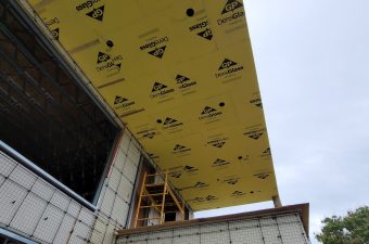 Yellow weatherproof building wrap on a construction site roof.