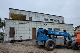 Construction site with a blue Genie lift and an unfinished building.
