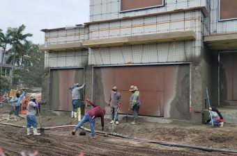 Four people painting a wall outside a building.