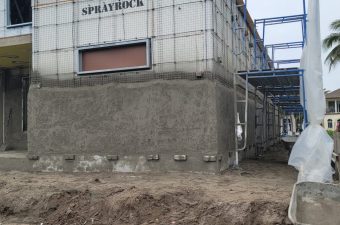 Construction site with concrete walls and scaffolding under cloudy sky.