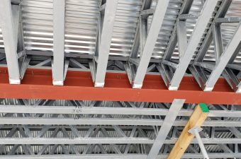 Red steel beam in a white ceiling framework with pipes.