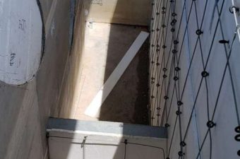 A narrow outdoor space between buildings with tiled walls and a pipe.