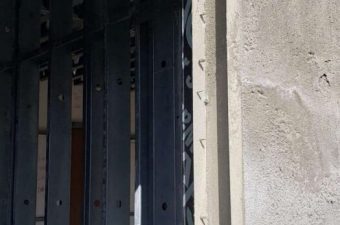 Metal gate with a lock on a textured wall.