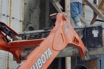 Kubota machinery arm in a construction site with workers nearby.