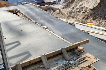 Concrete slab being prepared with wooden formwork at a construction site.