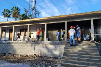 People working on a concrete structure under a clear blue sky.