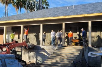 Workers building a house porch with solar panels on the roof.