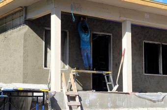 Worker plastering wall on building under construction at sunset.