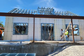 Construction workers building a concrete structure under a clear blue sky.