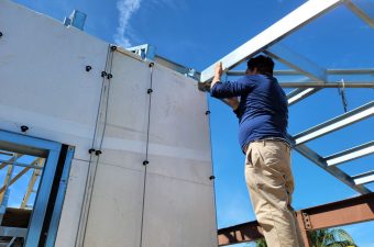 Technician working on rooftop air conditioning units under a clear sky.