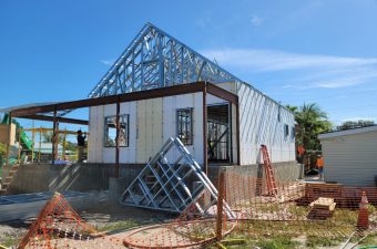 Modern house under construction with metal framing and blue sky.