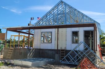 A house under construction with a glass pyramid roof structure.