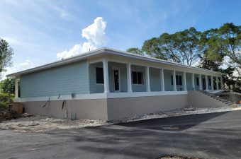 Single-story building with a large covered porch under a blue sky.