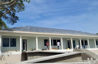 A modern single-story house with a spacious porch under a clear blue sky.