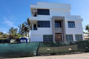 Modern white multi-story house under a clear blue sky.