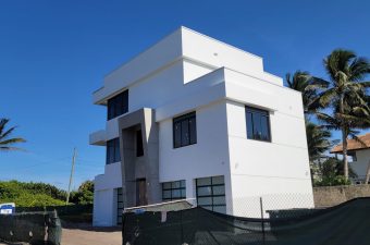 Modern white multi-story house with minimalist design under clear blue sky.