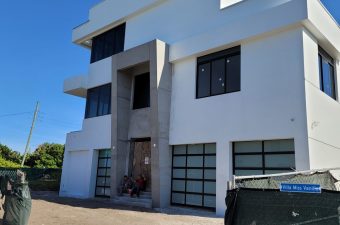 Modern white building with large windows and a clear blue sky.