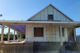 A partially constructed house with exposed concrete blocks and a clear blue sky.