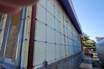 Large industrial cooling or ventilation unit with grid panels along a building.