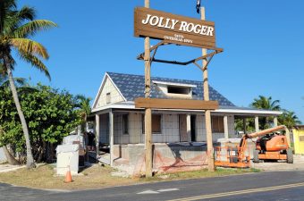 A rustic building with a large Jolly Roger sign overhead.