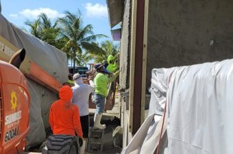 Workers unloading materials from a truck at a construction site on a sunny day.