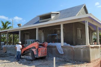 Construction site with a house being built and a compact loader working.