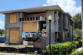 Abandoned building with boarded-up windows and no left turn sign.