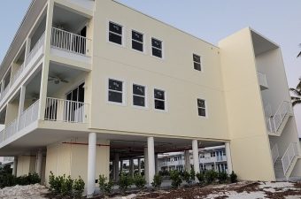 Modern beige building with multiple windows and balconies under a clear sky.