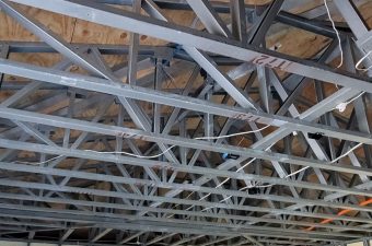 Steel truss framework supporting a wooden ceiling structure.