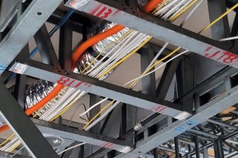 Ceiling structure with organized electrical wiring and metal beams.