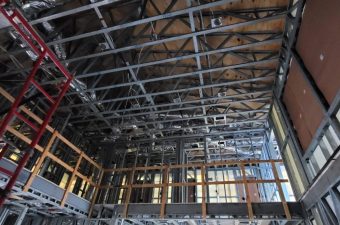 Interior view of a building under construction focusing on ceiling framework and ducts.
