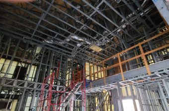 Interior construction site with exposed steel framework and scaffolding.